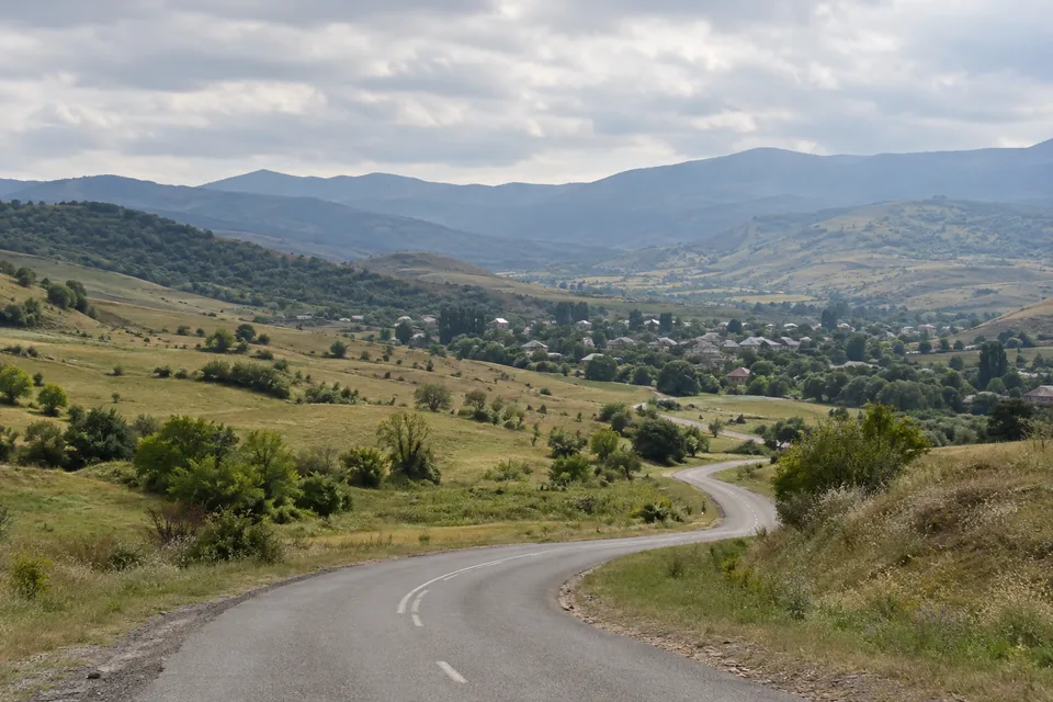 Illustrated foothill valley and rural road in Georgia, not a candidate property or named location.